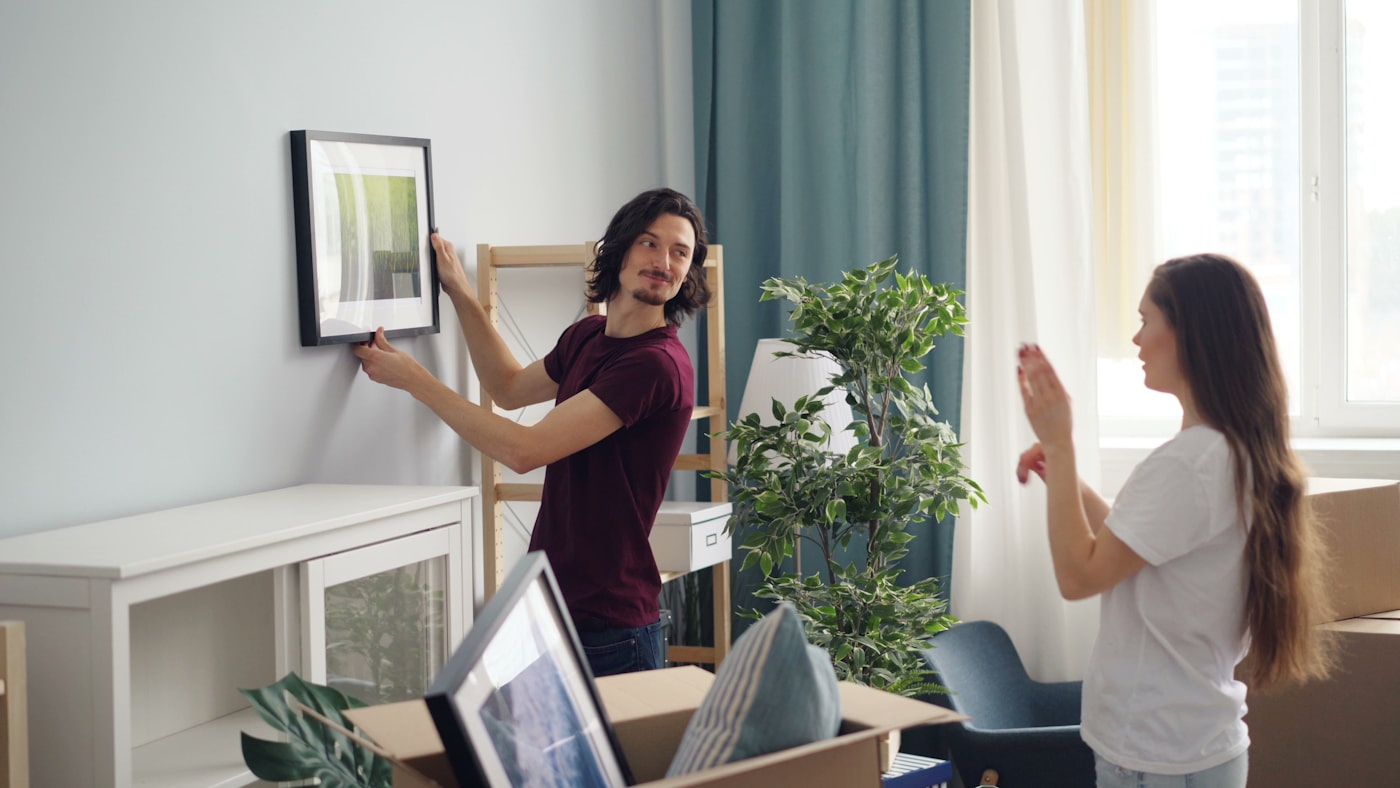 A couple settling framed art into their bright new San Francisco home after a move